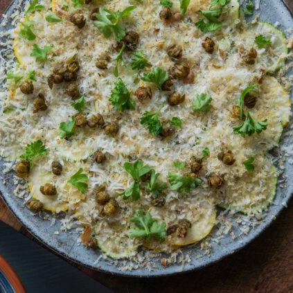 Courgette Carpaccio With Parmesan, Walnut And Crispy Caper Berries served on a plate
