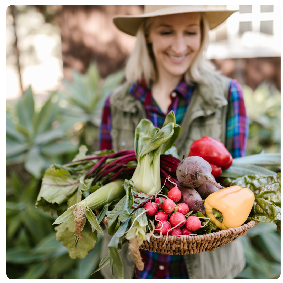 Woman holding a basket of fresh vegetables in a garden setting